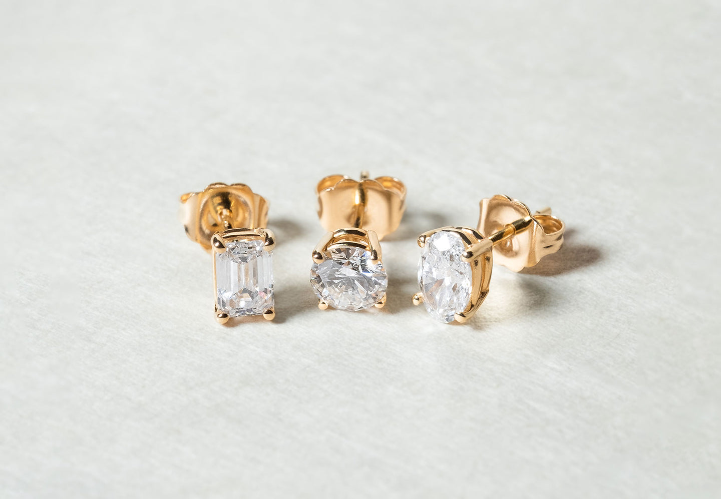 The Emerald Diamond Stud, The Round Diamond Stud, and The Oval Diamond Stud by Holden in yellow gold