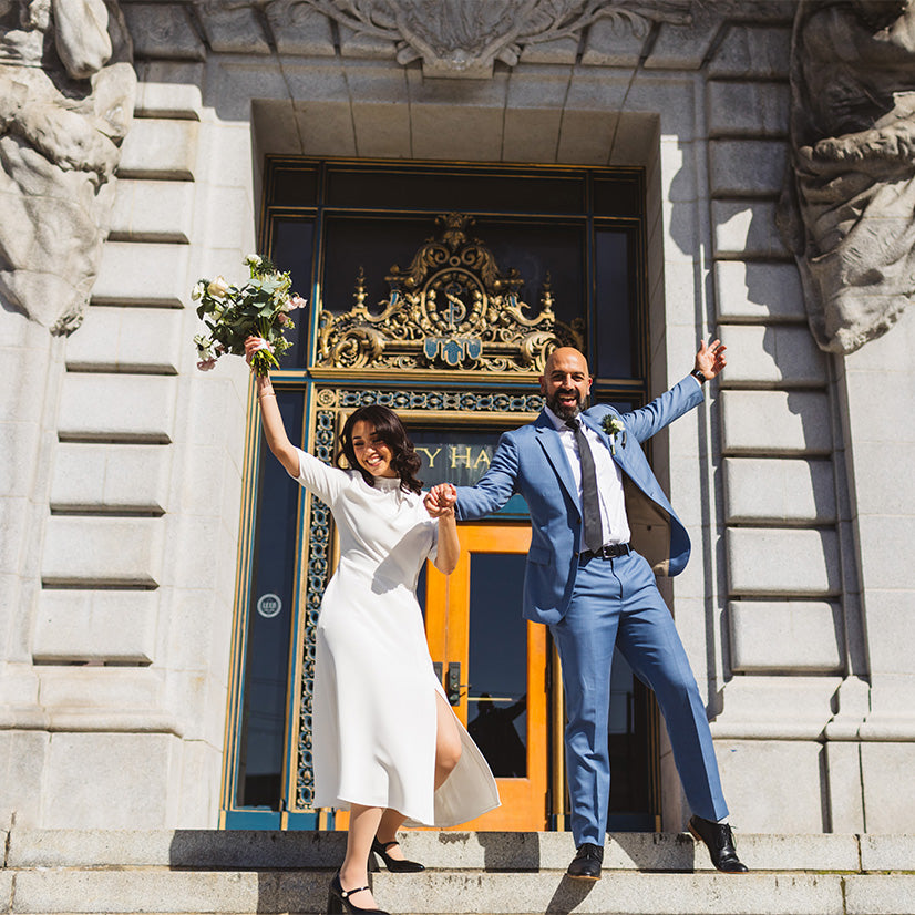 Bride and groom hold hands on steps in front of City Hall; courtesy of @zoelarkinphoto